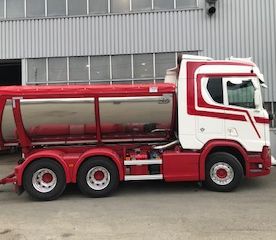 Rød og hvit lastebil foran lagerbygg